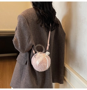 Pink plush sphere bag with white bow detail and clear beaded handle shown on shoulder