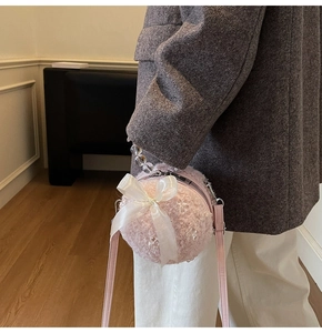 Detail of pink faux fur round handbag featuring a large chiffon bow and beaded handle