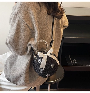 Detail of black plush sphere bag with white silk bow and transparent beaded handle