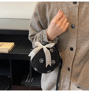 Chic black plush round bag with large white satin bow and pearl beaded handle detail