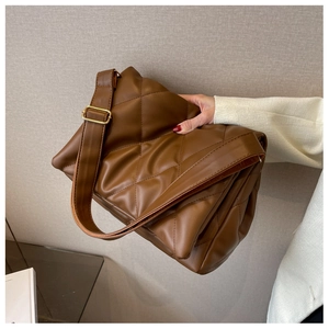 Close-up of brown quilted faux leather shoulder bag with gold hardware and wide strap