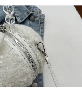 Detail of white plush barrel bag with clear beaded handle and silver metal hardware