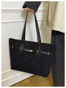 Détail d'un cabas noir en cuir mat avec boucle métallique dorée et bandoulières