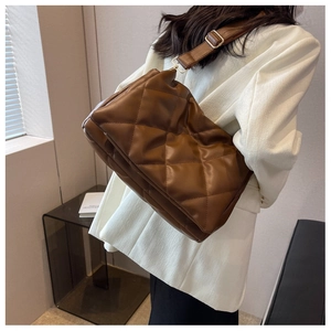 Detail of dark brown quilted shoulder bag with adjustable strap on white blazer