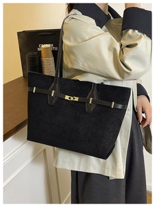 Détail d'un sac cabas noir mat avec boucle dorée et lanière en cuir sur le mannequin