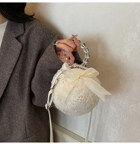 Close-up of white plush crossbody bag featuring tulle bow and beaded handle detail