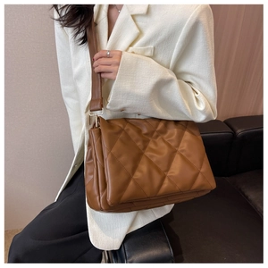 Detail of dark brown quilted shoulder bag showing soft faux leather texture and wide strap