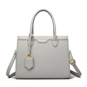Detailed macro of grey lychee leather texture with gold lettering on a tote handbag