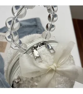 Detail of silver dual zipper on white plush handbag with elegant ribbon bow
