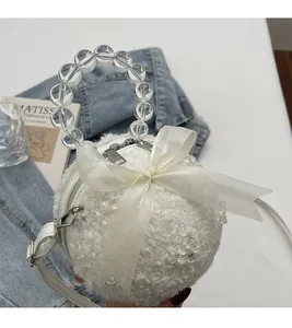 Close-up of a white plush spherical bag featuring a pearl handle and organza bow detail