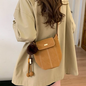 Brown faux suede bucket bag with plush charm and metal decor for minimalist casual styling