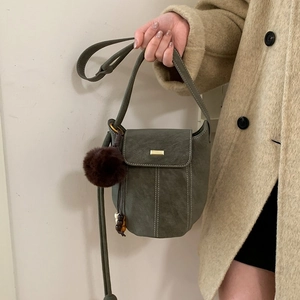 Minimalist faux suede bucket bag with contrast stitching and plush charm decoration