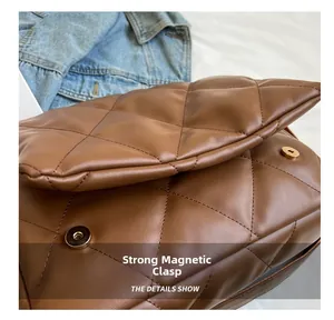 Detail of a brown quilted leather bag featuring a shiny gold magnetic closure clasp
