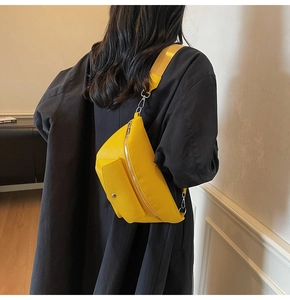 Close-up of bright yellow textured leather waist bag with silver metallic zippers