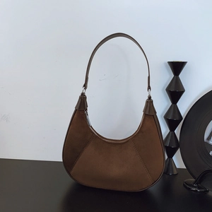 Retro brown crescent hobo bag in suede and smooth leather on a minimalist display