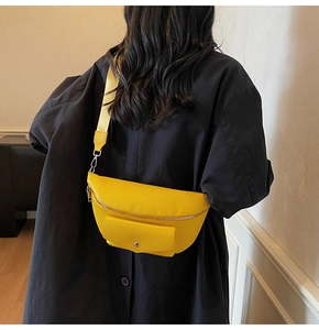 Close-up of bright yellow crossbody bag featuring pebble leather and metal buckle detail