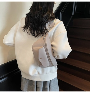Detail of light gray lychee grain leather crossbody bag with silver zipper and front flap pocket