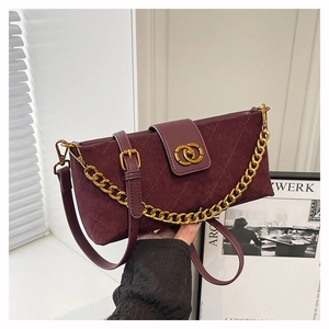 Detail of burgundy quilted suede shoulder bag with gold chain and metal buckle