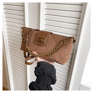 Detail of dark brown quilted crossbody bag with gold chain and metal ring buckle