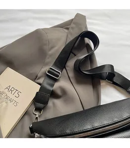 Close-up of black lychee leather waist bag with silver zipper and adjustable strap