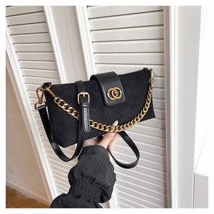 Detail of black quilted crossbody bag featuring a gold chain and suede-like finish