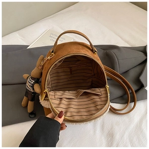 Detail view of brown plush backpack interior with striped lining and teddy bear charm