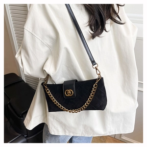 Detail of quilted black suede crossbody bag with gold chain and metal ring buckle