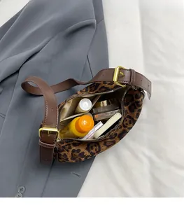 Detail of leopard print crossbody bag showing spacious interior with cosmetics
