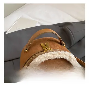 Detail of brown suede bag with white plush fur trim and golden metal handle hardware