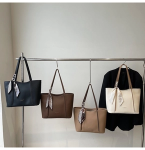 Row of four colorful leather tote bags with decorative silk scarves and sleek minimalist design