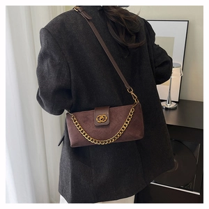 Detail of dark brown suede crossbody bag with gold chain and diamond quilted stitching