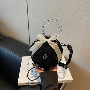 Mini black plush spherical handbag with a white silk bow and elegant beaded handle