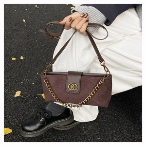 Detail of dark brown suede crossbody bag with gold hardware and classic quilting