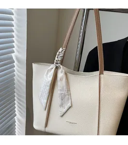 Detail of white lychee leather tote bag with brown handles and floral scarf decoration