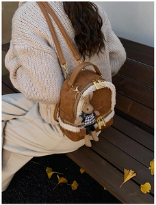 Detail of brown suede backpack with white faux fur trim and cute rabbit doll keychain