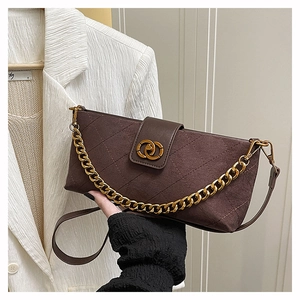 Detail of a brown suede rectangular bag with quilted patterns and dual gold rings