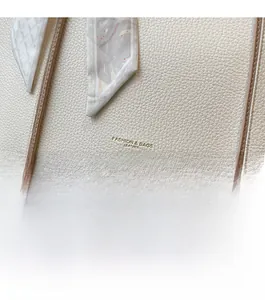 Detail of lychee pattern leather tote bag with gold logo and decorative floral scarf handle