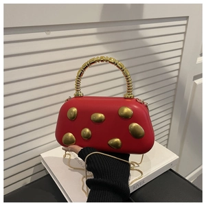 Detail of red leather underarm bag featuring a gold pebble accent and round metal handle