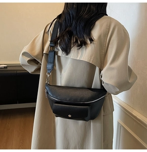 Detail of black pebbled leather chest bag with adjustable wide strap and metal hardware