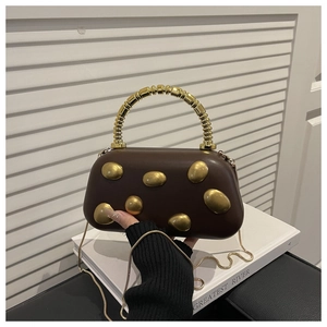 Detailed close-up of brown capsule bag with gold oval relief accents and beaded handle