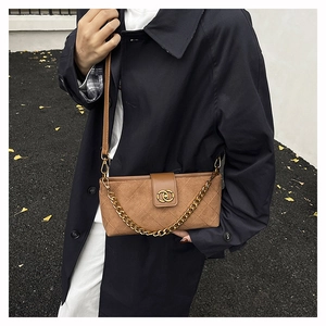 Close-up of brown suede crossbody bag featuring quilted patterns and gold chain detail