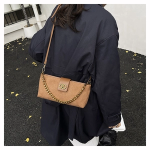Detail of camel suede crossbody bag with quilted pattern and gold chain on street