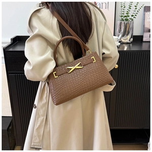 Détail du sac panier tressé marron avec fermoir en X doré et fine bandoulière en cuir
