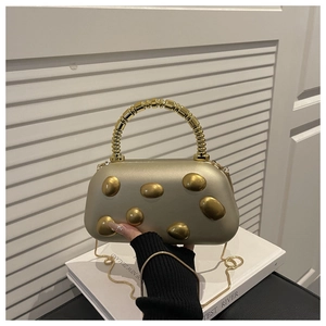 Detail of champagne gold hardshell evening bag with embossed metal and unique handle