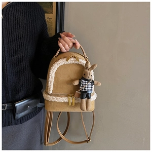 Detail of khaki suede mini backpack with plush shearling trim and a cute rabbit charm