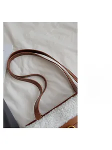 Détail du sac en peau de mouton blanche avec bandoulières en cuir brun et boucles d'or