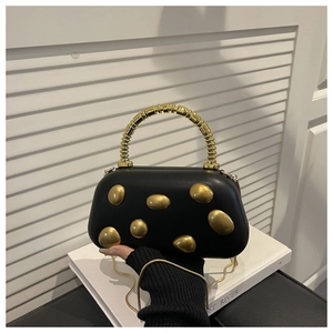 Detail of black hard shell clutch bag with irregular gold metal texture and bead handle