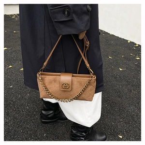 Detail of retro brown suede quilted bag with gold chain strap and metallic logo