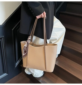 Detail of large beige leather tote bag featuring a decorative silk scarf and textured finish