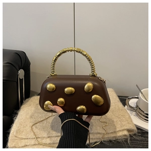 Detail of dark brown vintage chain bag with gold embossed metal accents and artistic handle